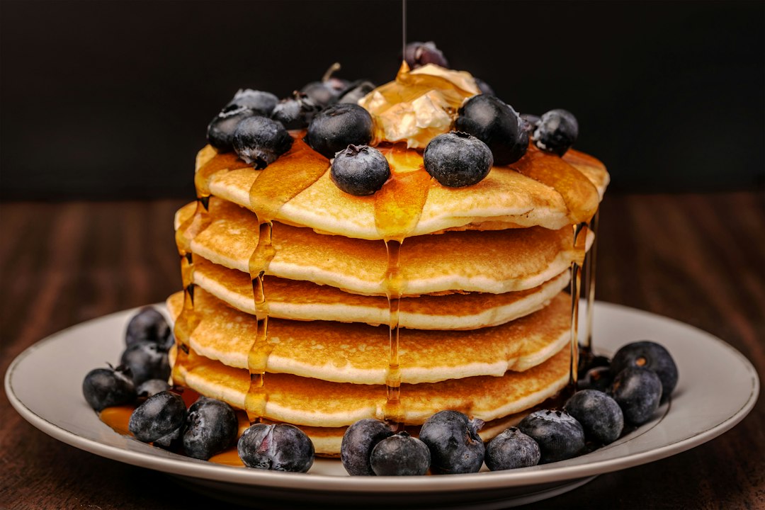 Stack of pancakes covered in blueberries and syrup.
