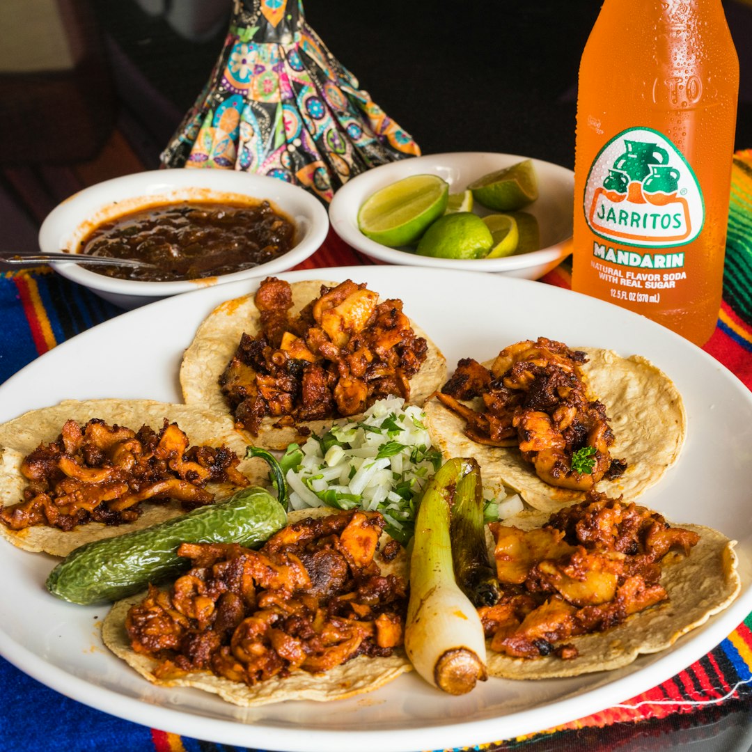 A plate of tacos de pulpo with a Jarritos Mandarin soda.