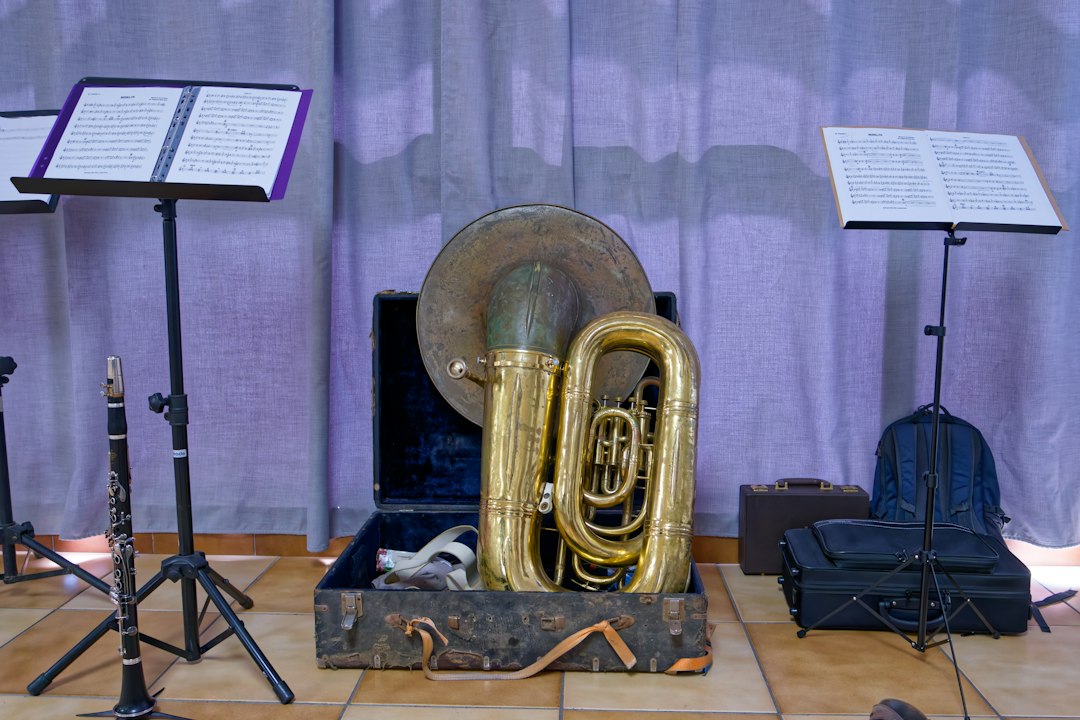 Brass tuba in an open case with music stands.