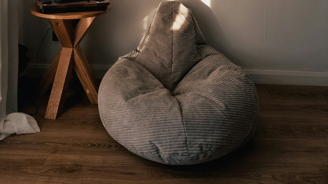A genuine corduroy beanbag chair, holding its shapeless ground beside a proper armchair-shaped world.