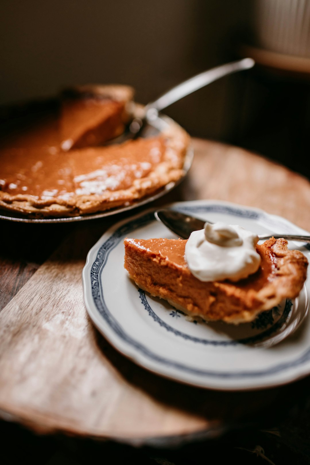 Homemade pumpkin pie with a slice on a plate.