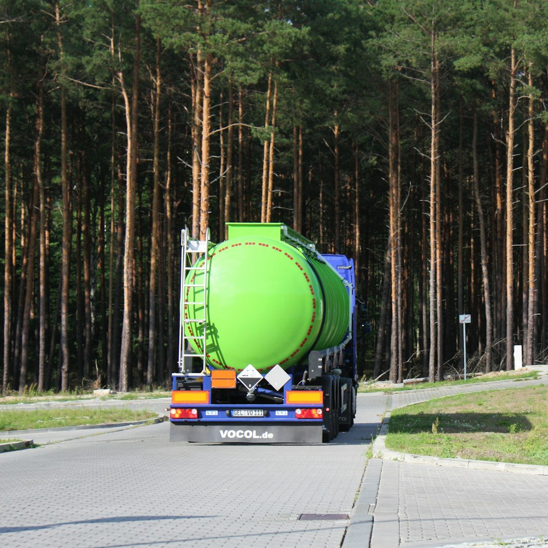 A verdant tanker truck in motion, flaunting its robust liquid-carrying capacity.