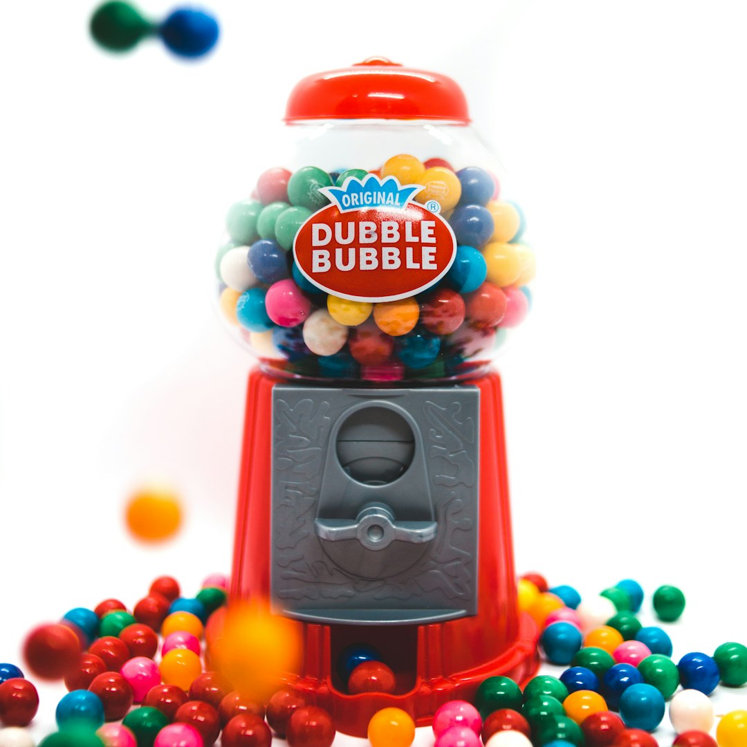 Gumball machine filled with colorful gumballs.