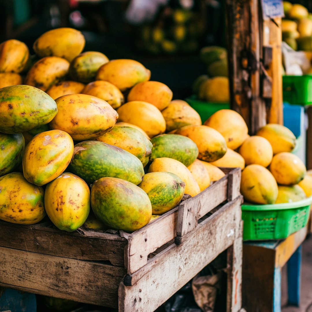 Fresh papayas piled high in wooden crates at a market.