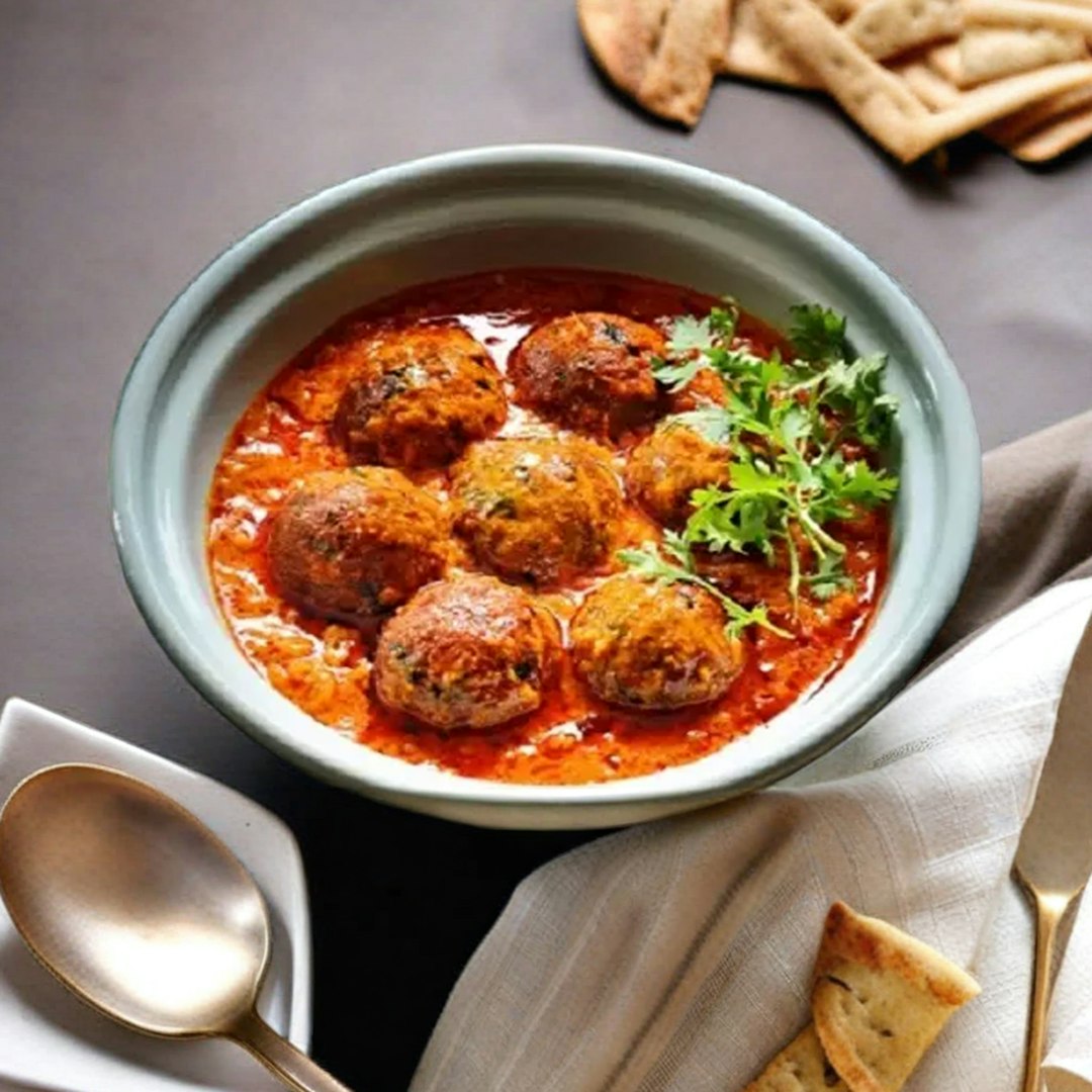 Bowl of meatballs in tomato sauce, garnished with cilantro.