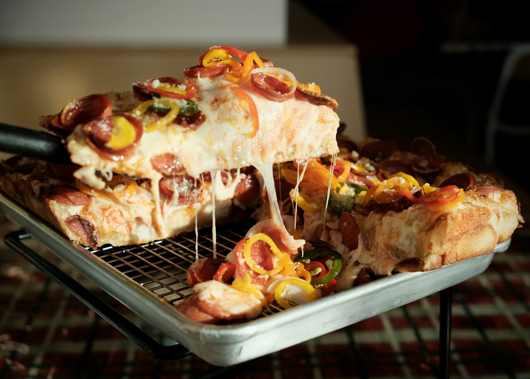 Slice of deep-dish pizza with melted cheese and toppings.