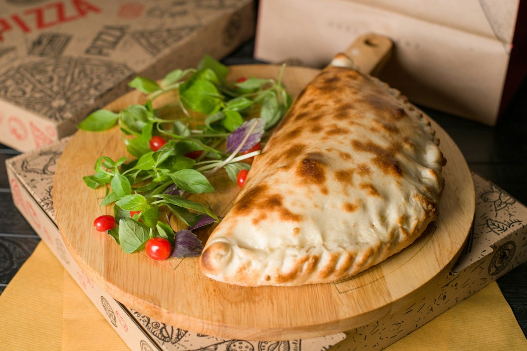Calzone on a wooden board with greens.