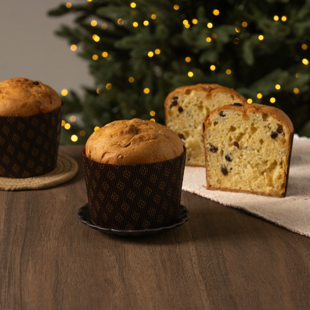 Four panettone cakes, one sliced, with Christmas lights.