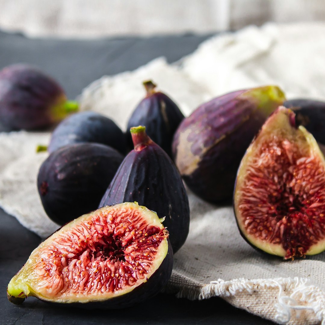 Whole and halved dark figs on linen cloth and slate.