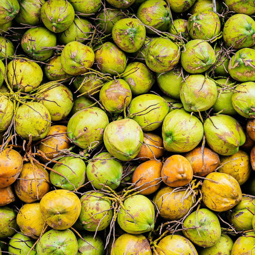 Pile of green and orange coconuts.