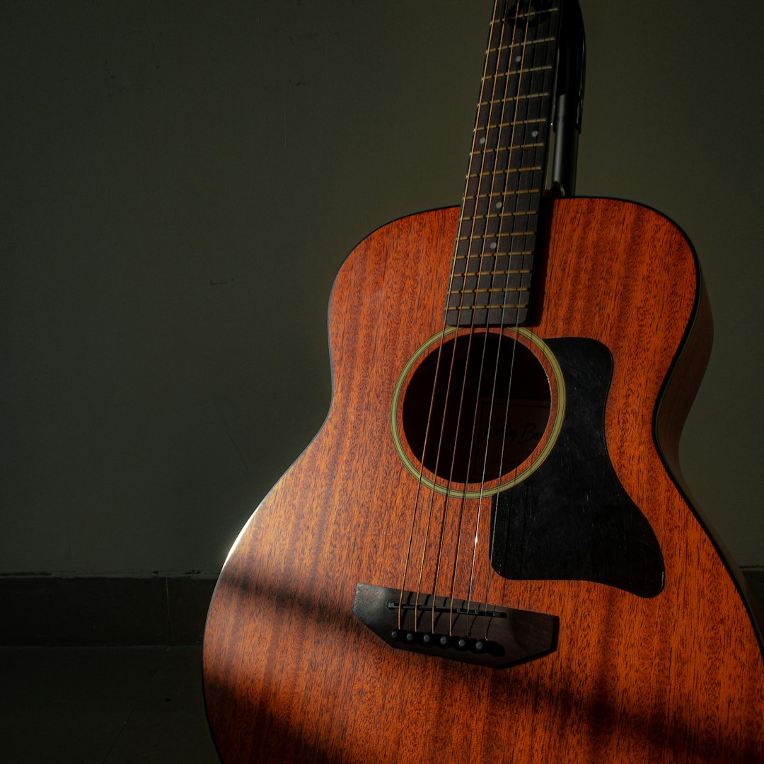 An acoustic guitar, body and soundhole, in low light.
