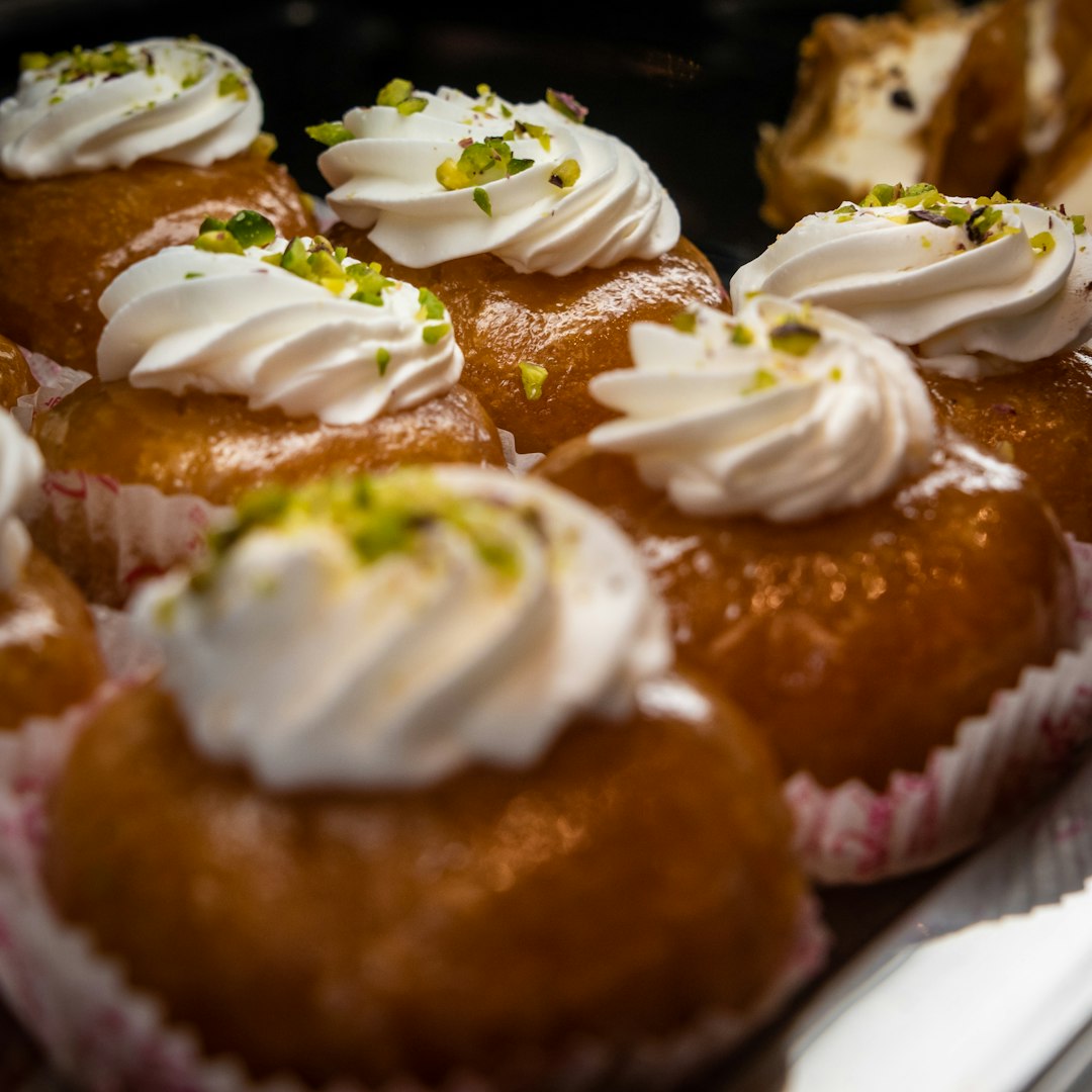 Close-up of rum baba desserts with cream and pistachios.