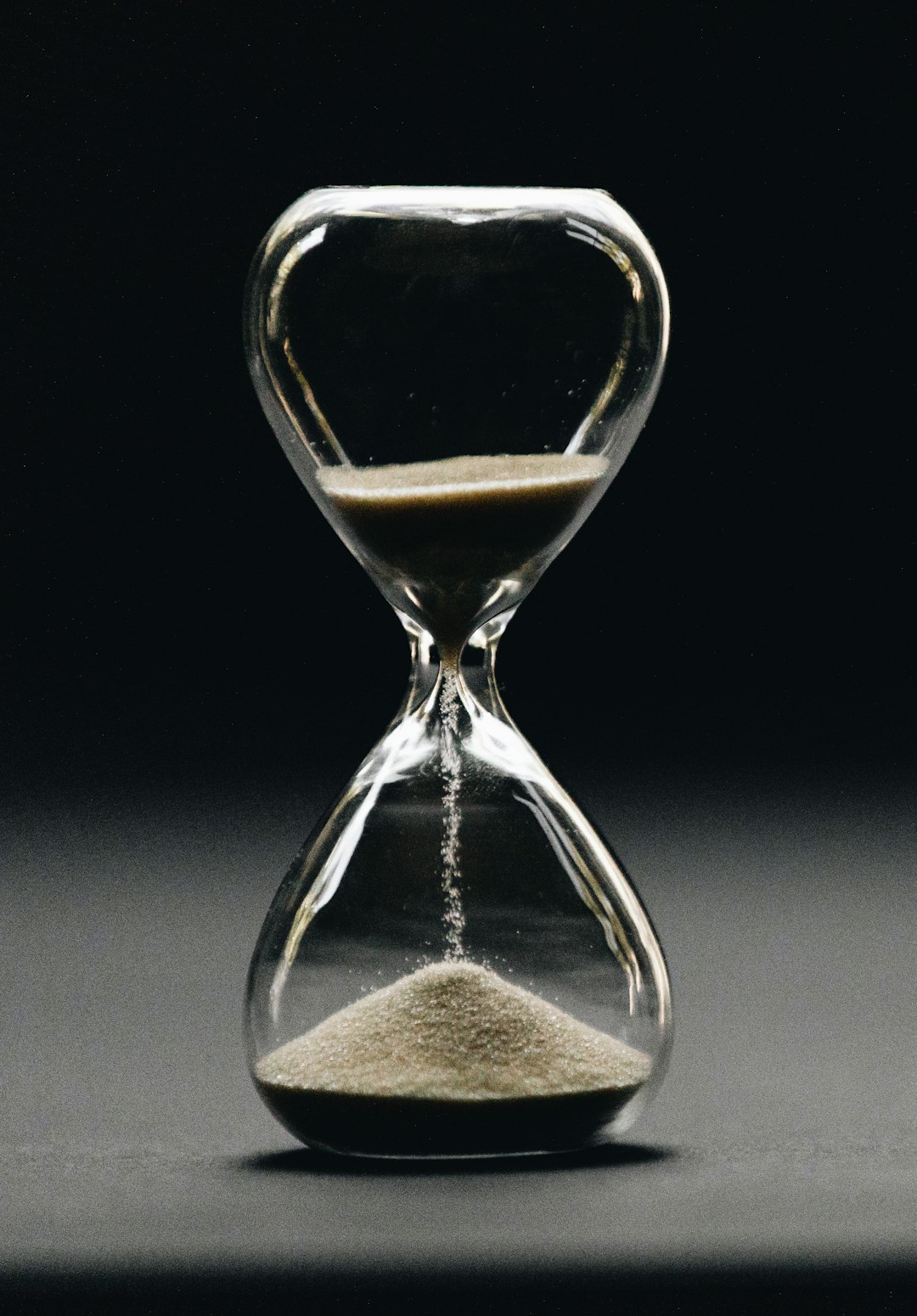 An hourglass, front view, the lower bulb filling.